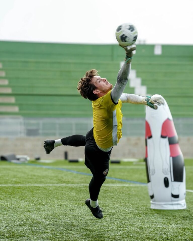 Portiere che respinge il pallone di pugno durante un allenamento